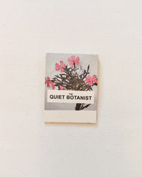 Botanical Matches by The Quiet Botanist feature a pink floral illustration on a light grey box—making this charming matchbook the perfect candle accessory for any space.