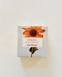 A square box with an orange flower on a light background, labeled Everyday. Handmade Soap by The Quiet Botanist—features natural fragrance and is perfect for sensitive skin.