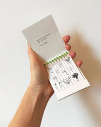 A hand holds The Quiet Botanist’s Golden Finch - Botanical Matches, a limited edition matchbook featuring biodegradable matches with botanical illustrations and the inscription: Solitude is not a place to hide. It is a place to be found.