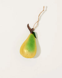 The Cody Foster Orchard Pear in Yellow + Green is a hand-crafted ornament with yellow-green coloring, a brown stem, green leaf, and hanging twine—an elegant decoration shown on a white background.