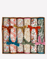 A box of six Meri Meri x Liberty Fall Crackers, each wrapped in Liberty floral prints and tied with a colorful velvet bow, arranged neatly in two rows.