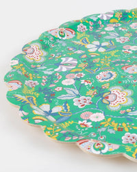 A close-up of the Meri Meri x Liberty Green Mabelle Large Tray by Meri Meri, featuring a scalloped edge and a vibrant green background adorned with colorful Liberty floral patterns in white, red, yellow, and blue.