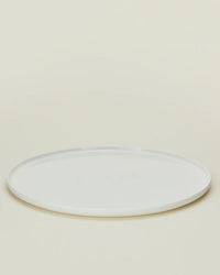 A set of four Simple Porcelain Dinner Plates by Hawkins New York is shown on a light beige background, each plate round, plain, white, and photographed from a slightly elevated angle.