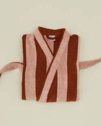 The Hawkins New York Simple Striped Terry Bathrobe in Blush/Terracotta, made from 100% cotton, features wide vertical stripes and a partially visible belt, combining comfort and style on a neutral beige background.