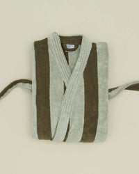 A folded Hawkins New York Simple Striped Terry Bathrobe in Olive/Sage, made from 100% cotton, with wide vertical stripes, is displayed on a light beige background. Its belt rests loosely at the sides.