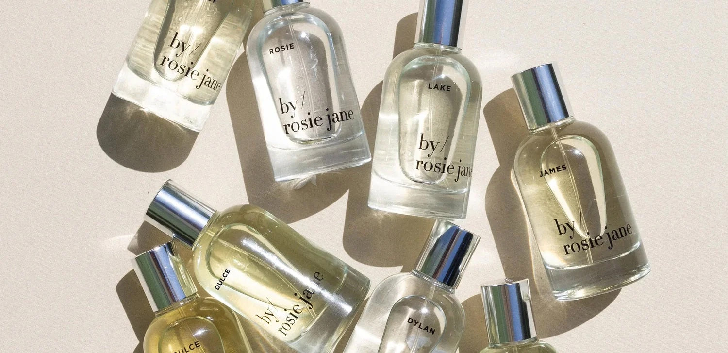 An overhead shot of eight perfume bottles made by the brand Rosie Jane