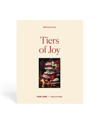 The Tiers of Joy - Food+Wine Collab 1000 Piece Puzzle by Piecework Puzzles features assorted desserts and cakes. The box has a minimalist cream background with red Food & Wine and Piecework logos at the bottom.