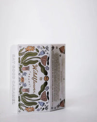 A rectangular Wildflower Caramel Co Assorted 6 piece box of Caramels features whimsical flower and green leaf drawings, "EAT GOOD CARAMEL" on the side, and is set against a plain white background.