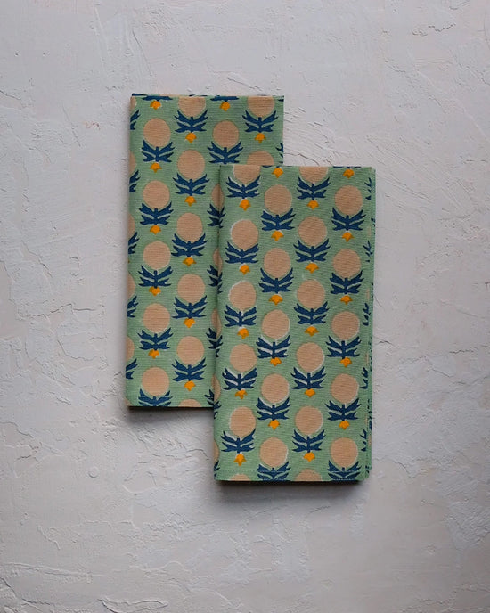 Set of four Kesya Table Napkins in Sage by Soil to Studio, featuring a repeating blue, yellow, and beige thistle flower print on a light green background—perfect for adding handmade charm to your table decor.