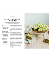A pistachio chocolate cheesecake with green-tinted whipped cream, featured in "Cookbook: Crumbs of Joy" by Cozy Publishing, sits on a stand with a served slice—ideal for Nordic food lovers and fans of Finnish recipes.