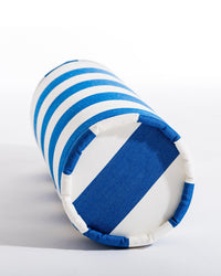 The Business & Pleasure Co Bolster Pillow - Crew Mediterranean Blue Stripe is shown lying on its side against a white background, featuring blue and white horizontal stripes with a bold blue stripe across one end.