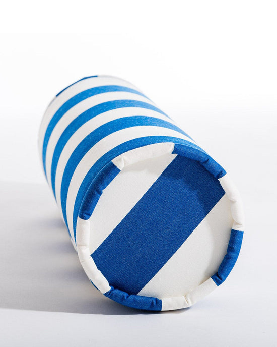 The Business & Pleasure Co Bolster Pillow - Crew Mediterranean Blue Stripe is shown lying on its side against a white background, featuring blue and white horizontal stripes with a bold blue stripe across one end.