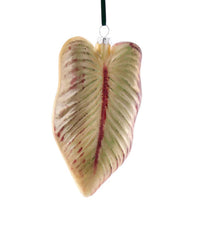 The Cody Foster Purple Glass Leaf Ornament features a hand-crafted heart-shaped leaf design with purple hues and is suspended by a black ribbon against a white background.