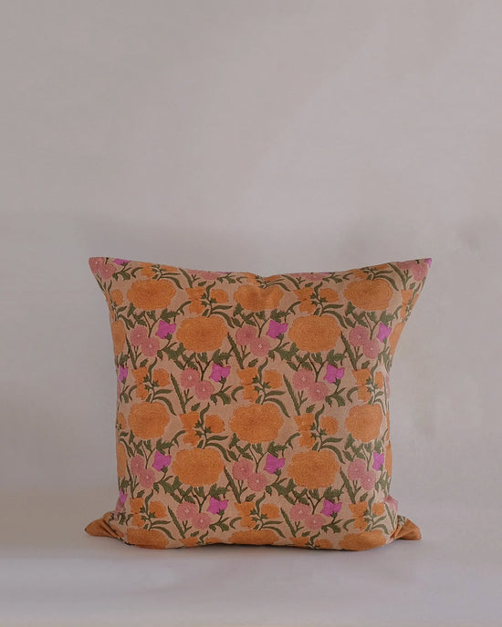 The Nargis Linen Pillow by Soil to Studio (18 x 18 in, Old Rose) features a vibrant orange floral hand block print with green stems and pink accents on beige, inspired by the Valley of Flowers—perfect for elevating any linen pillowcase collection.