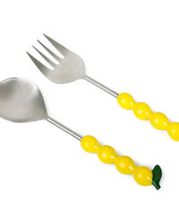The Casa Amarosa Salad Servers with Lemon Handles S/2 feature stainless steel heads, yellow lemon-shaped handles, and a green leaf detail on one handle, shown on a white background.