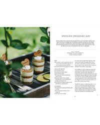 Three small glass jars of Vegalicious Cheesecakes – Bakery-Style & Plant-Based by Cozy Publishing, each layered with cookie crumbs and topped with whipped cream and a heart-shaped cookie, make for delicious egg- and dairy-free dessert inspiration.