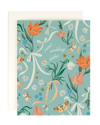 The Amy Heitman "Sweet Wedding Wishes" single card features cursive text on a teal background with orange flowers, butterflies, ribbons, and stars. Comes with an off-white envelope and has a blank interior for your message.