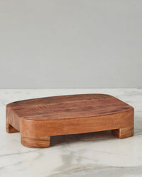 The etúHOME New Classic Rectangle Trivet Riser, Small—crafted from reclaimed wood with short, wide legs—rests on white marble against a plain gray background, showcasing its timeless design as a must-have kitchen essential.