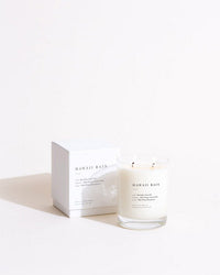 The Brooklyn Candle Studio Hawaii Rain Classic 2-Wick Candle, in a clear glass jar, is shown before its matching white box on a light surface with a minimalist background.