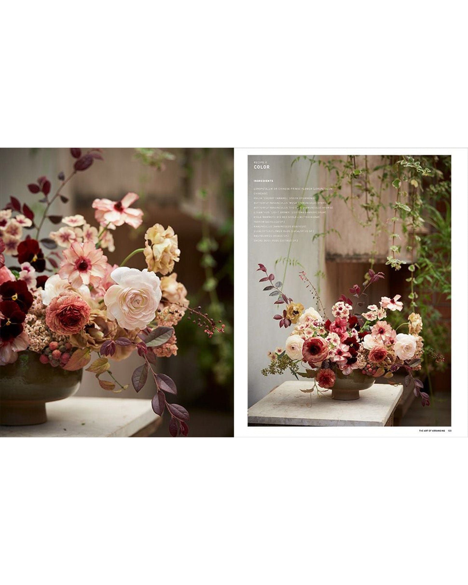 The Artistry of Flowers by Random House features a vibrant floral arrangement in a ceramic bowl with pink, white, and burgundy flowers. Set near trailing green plants, it’s an elegant decor accent for any neutral space.