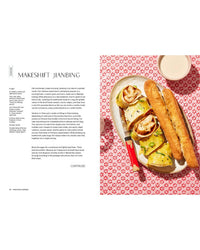 A plate with rolled jianbing, two baguettes, and a cup of milk sits on a red-and-white floral tablecloth. On the left, Snacking Dinners by Chronicle Books shares a makeshift jianbing recipe for your next meal or snack.