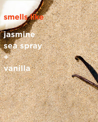 A coconut half, two vanilla pods, and "smells like jasmine, sea spray + vanilla" written on sand capture the refreshing essence of Rosie Jane’s Madie Everyday Hydrating Body Oil for nourishing and hydrating your skin.