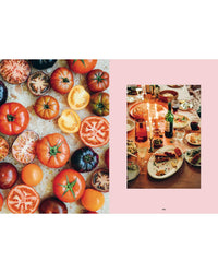 An overhead view features colorful tomatoes beside a Nordic-inspired table with wine and dishes, evoking a joyful meal—perfectly capturing the spirit of "Cookbook: Crumbs of Joy" by Cozy Publishing.