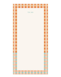 The Camp Check List Pad by Amy Heitman is a rectangular notepad with “TO DO” at the top and an orange, peach, and blue checkered border. Tear-off sheets offer a blank white center for jotting down tasks.