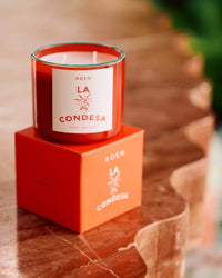 A ROEN La Condesa Candle, made with premium fragrance oils and coconut soy wax, sits on its box atop a glossy marble surface as sunlight casts warm shadows.
