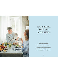 A man and woman share breakfast, smiling as a dog looks in from the window. Right side reads EASY LIKE SUNDAY MORNING on light blue, evoking Nordic coziness. Featuring Cookbook: Crumbs of Joy by Cozy Publishing.