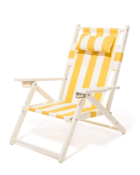 The Tommy Chair - Acacia White - Crew Mimosa Yellow Stripe by Business & Pleasure Co features a white frame, yellow-and-white striped canvas sling, and matching cushioned headrest, pictured against a plain white background.