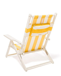 The Tommy Chair - Acacia White - Crew Mimosa Yellow Stripe by Business & Pleasure Co features a white wooden frame, UV-resistant yellow and white striped canvas, a back pocket, and is shown from the rear at an angle.