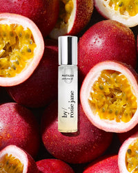 Rosie Jane's Perfume Oil in Matilda is set among halved passion fruits with vivid yellow pulp and seeds, creating a vibrant tropical scene that suggests a passionfruit-inspired fragrance.