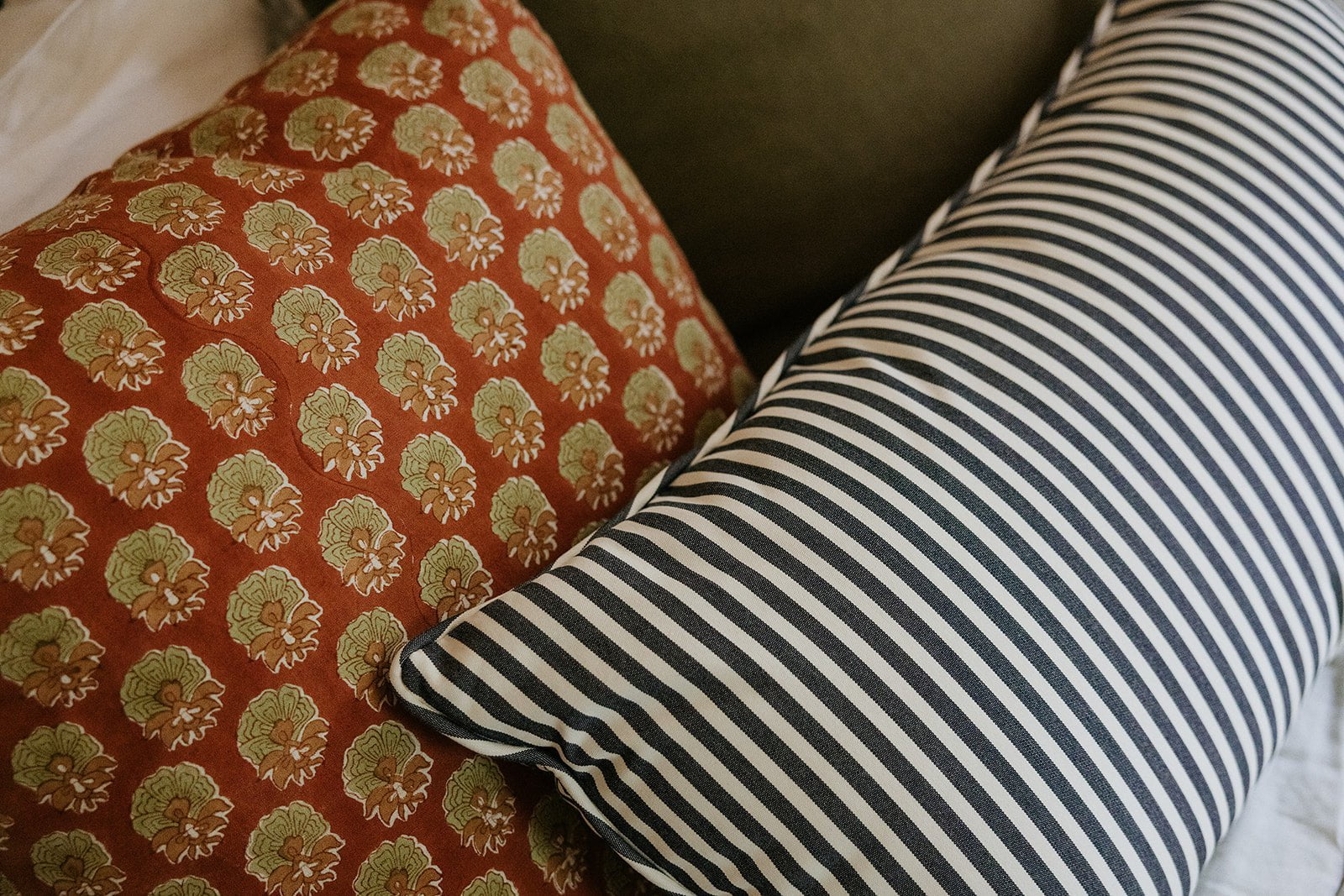 Two pillows, one with a floral pattern and the other with black and white stripes, on a couch.