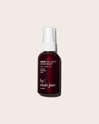 A maroon spray bottle of Rosie Jane’s Calm Full Body Deodorant sits on a light beige background. This aluminum-free deodorant is made for sensitive skin with soothing lavender, chamomile, and vanilla scents.