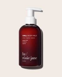 A dark amber pump bottle labeled Chill Body Milk by Rosie Jane, with hydrating peppermint, mandarin, and cypress scents, is displayed on a light beige background.