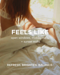 A woman in white lingerie relaxes on a sunlit bed by an open window. Text: FEELS LIKE open windows, naps, sunset walks. Hydrate, BRIGHTEN, BALANCE your skin with Rosie Jane Chill Body Milk—refreshing body milk for radiant skin.