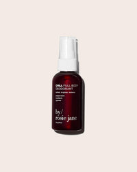 A burgundy Chill Full Body Deodorant spray bottle by Rosie Jane, with a white nozzle and text, sits on a light beige background. This natural deodorant is formulated for sensitive skin.