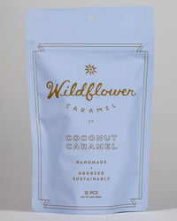 A resealable light blue bag from Wildflower Caramel Co, labeled "Coconut Caramels (Vegan)," contains 12 handmade, sustainably sourced vegan caramels.