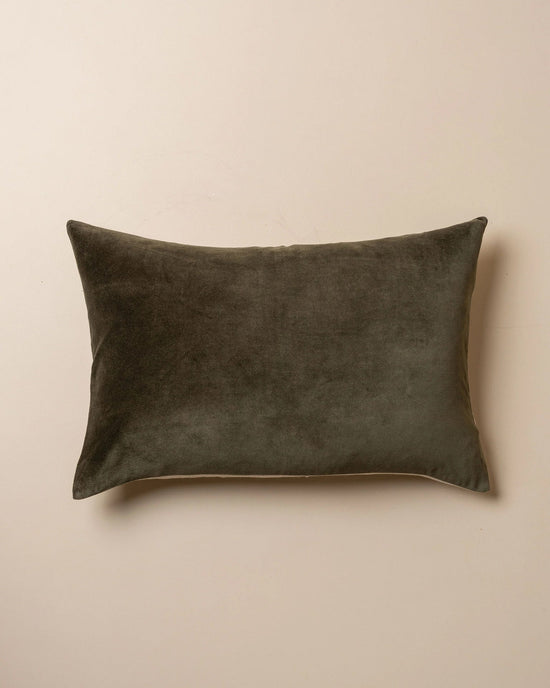 The Saarde Velvet Lumbar Pillow with Feather Insert in Dark Olive rests on a plain beige surface.