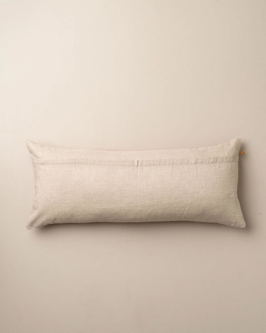 The Saarde Velvet Body Pillow with Feather Insert in Nutmeg rests against a plain light-colored wall.