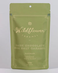 A green resealable bag from Wildflower Caramel Co labeled Dark Chocolate Sea Salt Caramels in a Bag, featuring handmade fair trade caramels. Contains 12 pieces and weighs 6 oz (184g).