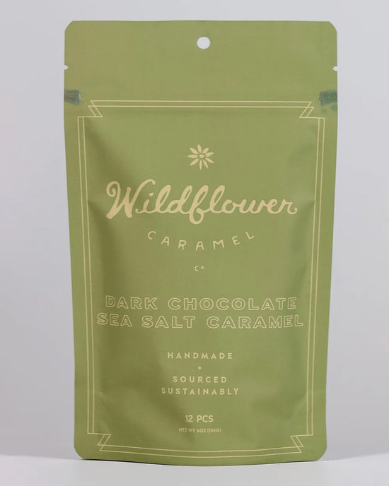 A green resealable bag from Wildflower Caramel Co labeled Dark Chocolate Sea Salt Caramels in a Bag, featuring handmade fair trade caramels. Contains 12 pieces and weighs 6 oz (184g).