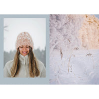 A woman in a pink knit hat and fleece jacket smiles in a snowy landscape, evoking the cozy charm of winter as inspired by "Four Seasons of Cabin Cooking" from Cozy Publishing.