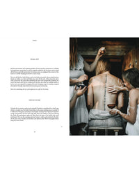 In a rustic wooden setting, three women dressed in white apply Nordic Magic sauna salt by Cozy Publishing in artistic lines on another woman’s back, all illuminated by soft natural light to evoke Nordic traditions.
