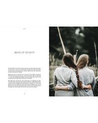 Two women outdoors, their long hair braided together into one plait—a nod to Nordic traditions—wear gray shirts against a green backdrop. Discover this scene and more in "Nordic Magic" by Cozy Publishing.