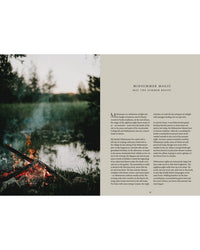 A campfire glows by a calm lake at dusk, with smoke rising amid trees and grass. On the right is Cozy Publishing’s Nordic Summer Cookbook—featuring Nordic recipes perfect for your midsummer table.