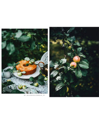 A round cake and fresh apples on a lace-covered outdoor table evoke Nordic summer recipes, as featured in the "Nordic Summer Cookbook" by Cozy Publishing, with apple branches and green leaves enhancing the seasonal mood.