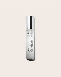 A clear glass bottle of Rosie Jane Perfume Oil in Dylan with a silver cap sits on a light beige background, showcasing this unisex fragrance’s effortless sophistication.