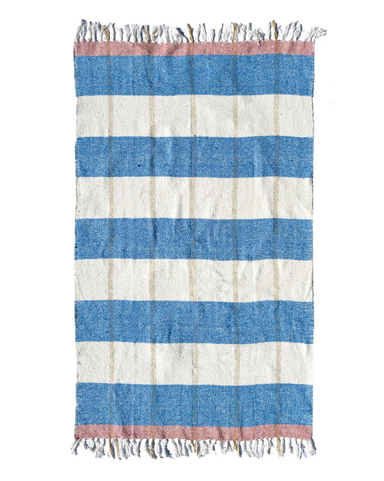 The Suave Aire - Blanket Roll by caminito features horizontal blue and off-white stripes with pink bands at each end, fringed edges, and a slightly rough, handwoven texture reminiscent of natural fiber blankets.